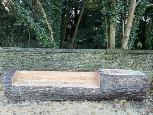 A hollowed-out log placed outdoors, surrounded by trees.