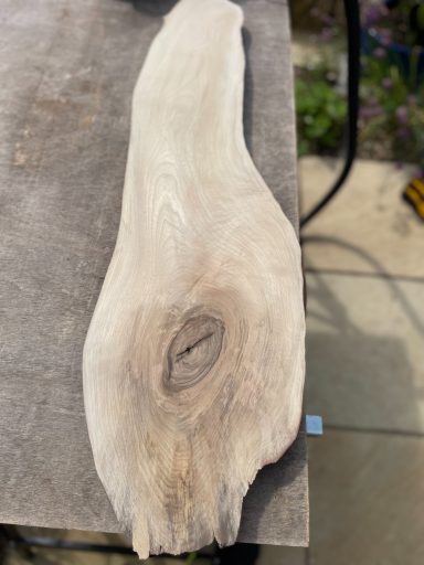 A smooth, elongated piece of light wood with a distinct knot.