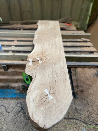 Smooth, wooden slab with natural edges, resting on a workbench.